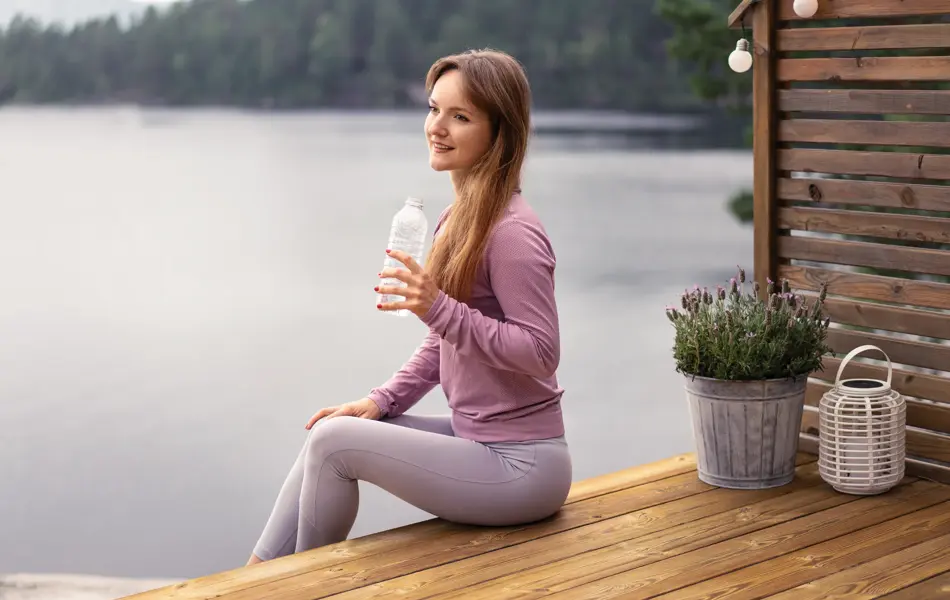 A girl is drinking water by the lake