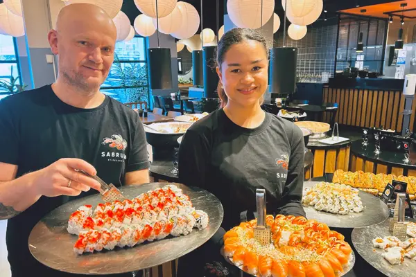 To som holder sushi og smiler til kameraet