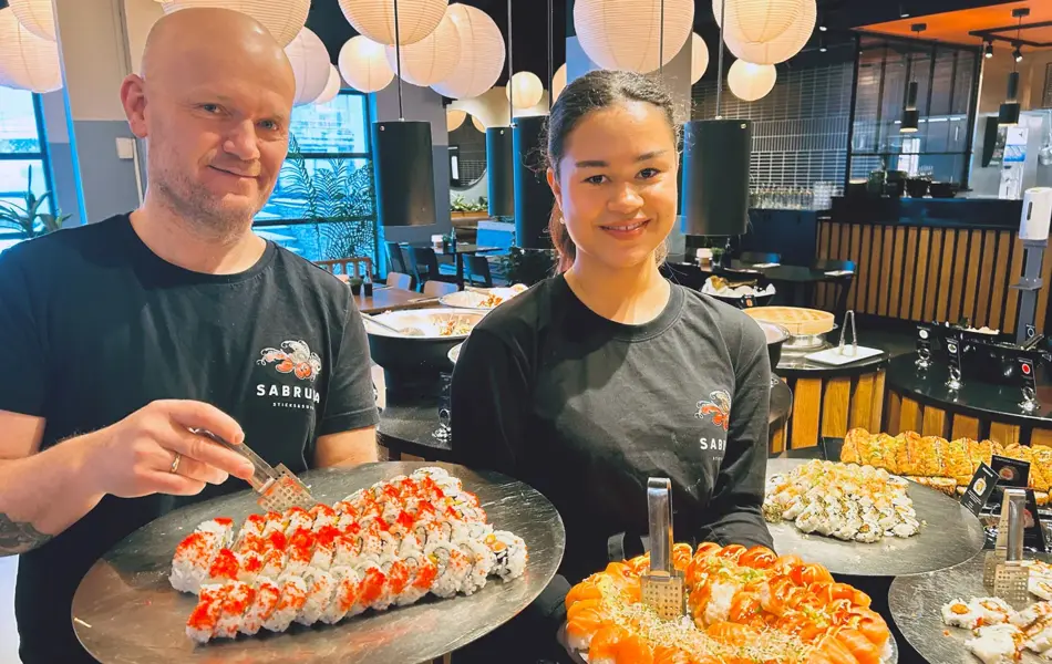 To som holder sushi og smiler til kameraet