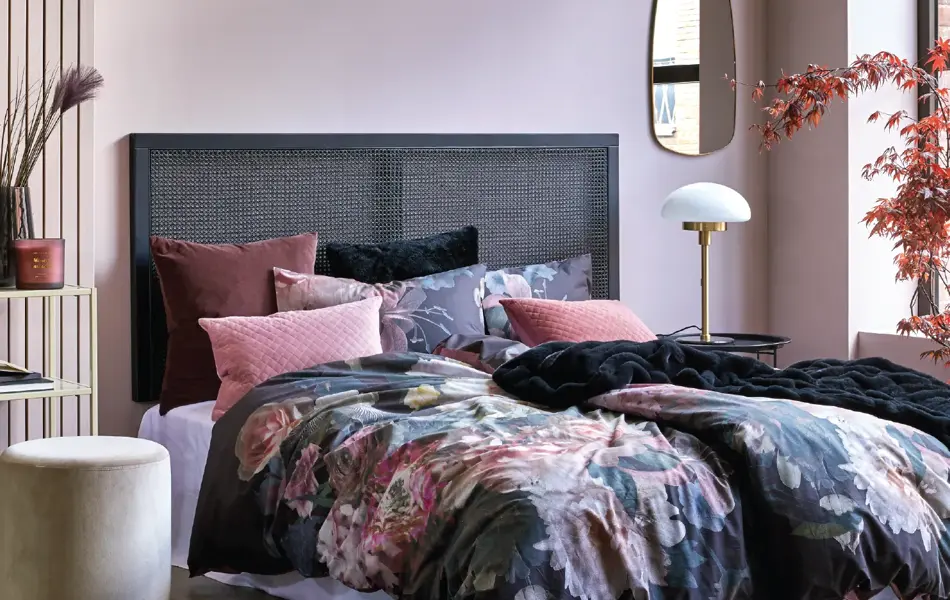 Seng med blomster sengesett og rosa vegg