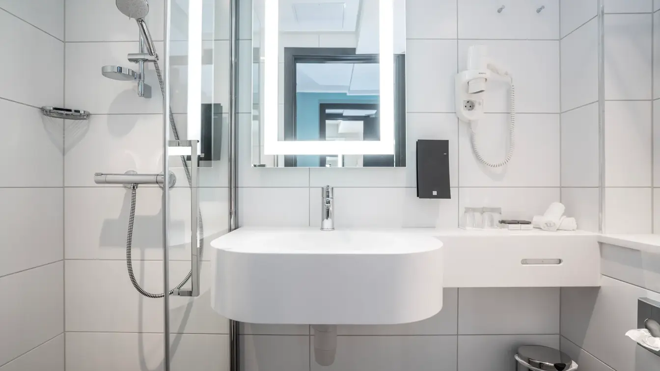 Vask, speil med led lys rundt, hårtørker og dusj på bad i dobbelt rom på Thon Hotel Bristol Bergen