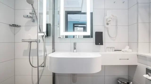 Vask, speil med led lys rundt, hårtørker og dusj på bad i dobbelt rom på Thon Hotel Bristol Bergen