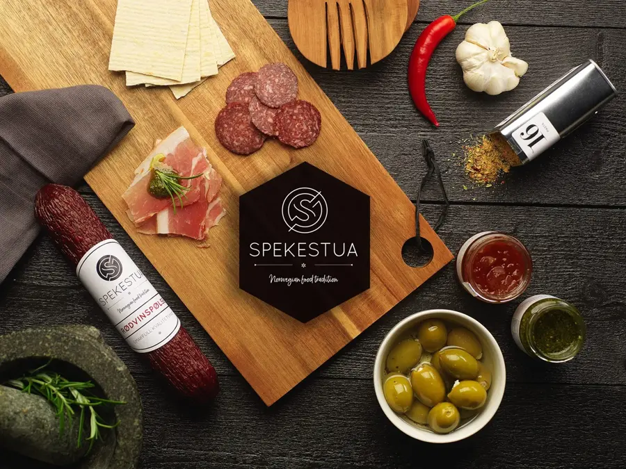 Utvalg av tapas med pølser, krydder og oliven på ei trefjøl