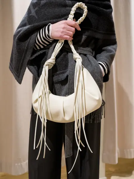 Dame holder en hvit veske med frynsedetaljer