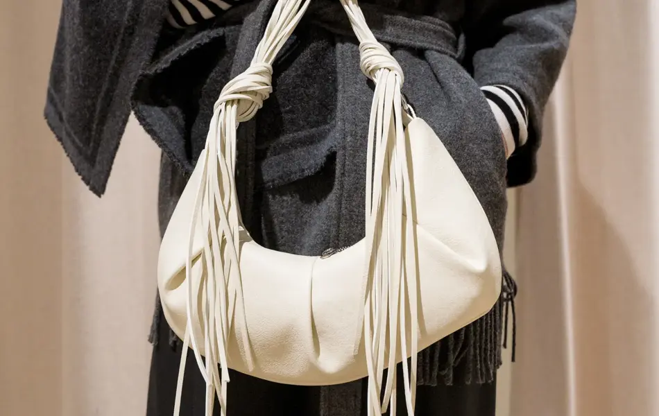 Dame holder en hvit veske med frynsedetaljer