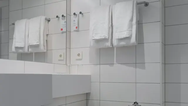 Vegghengt toalett og stort speil på bad med hvitte fliser.  I business rom på Thon Hotel Norge i Kristiansand