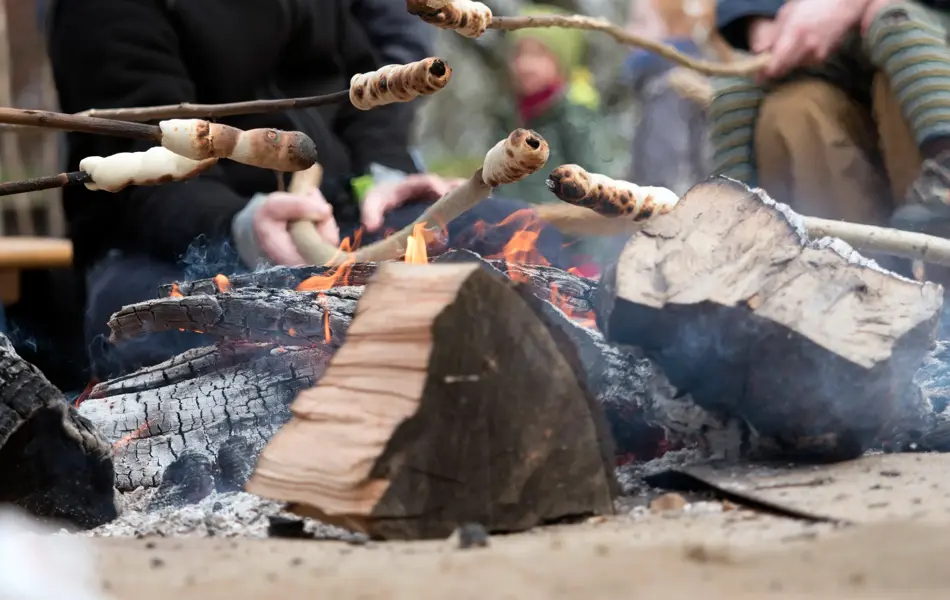 Family grilling bread on a stick over an open fire
