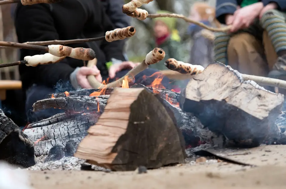 Family grilling bread on a stick over an open fire