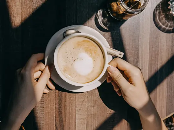 Top view of woman sitting by the window in coffee shop enjoying the warmth of sunlight and drinking coffee