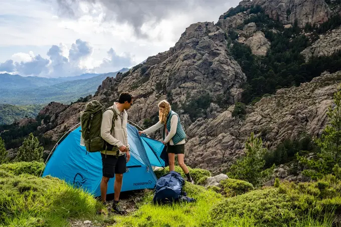 To som setter opp et telt i en fjellside