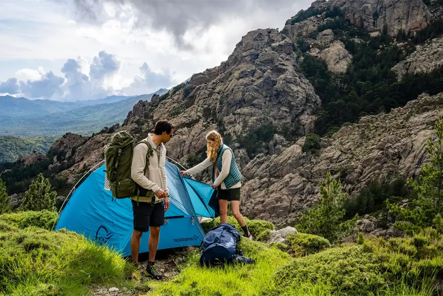 To som setter opp et telt i en fjellside