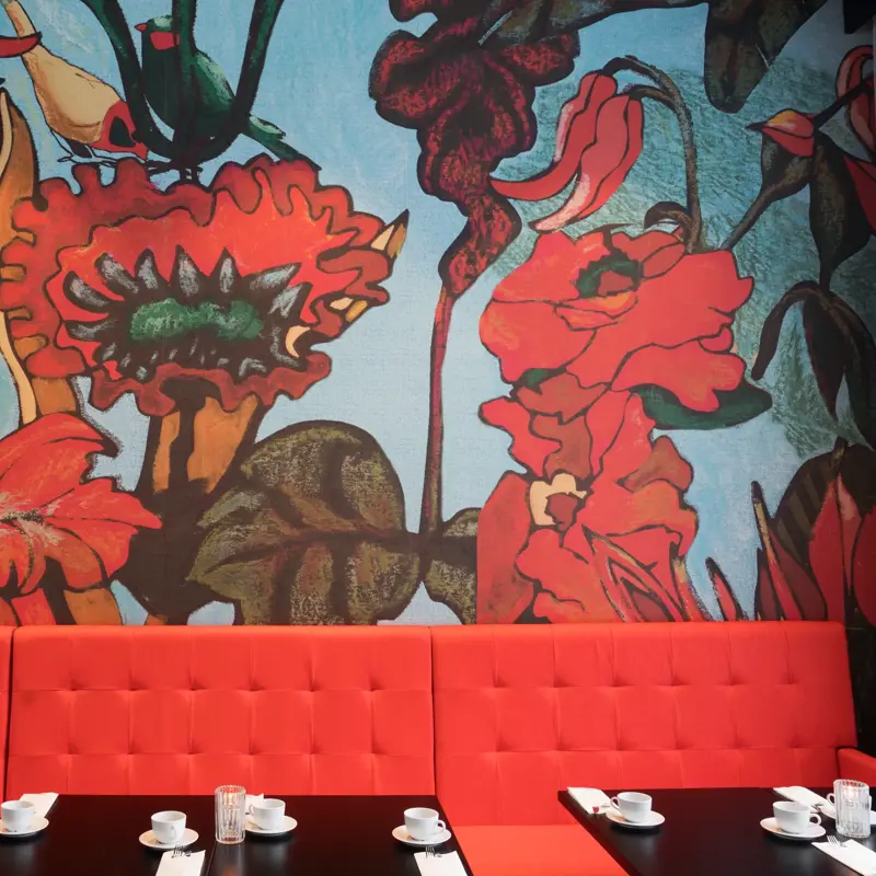 Knall rød sofa med røde store blomster på tapet i bagrunnen i restaurant på Thon Hotel Kirkenes ved kaia i Kirkenes sentrum