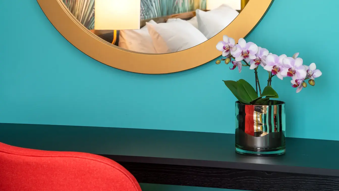 Rundt speil som reflekterer seng og tapet på rom på Thon Hotel Storo