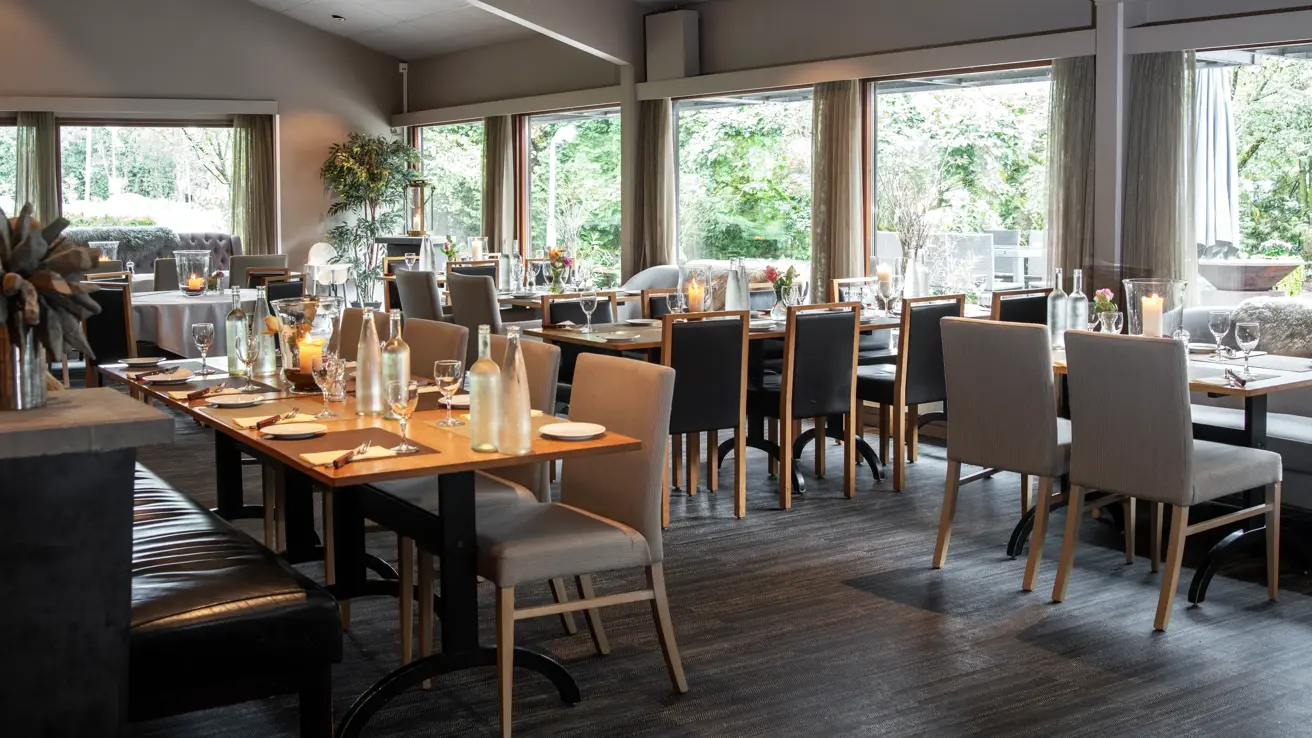 Flere langbord dekket med servise i en restaurant. 