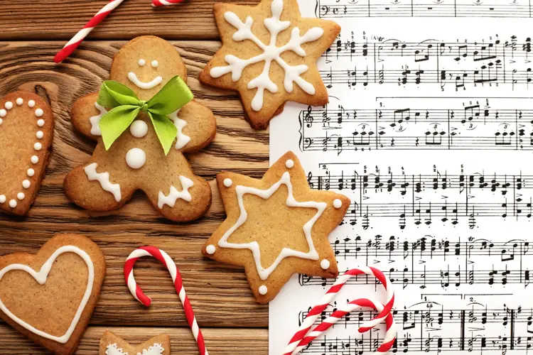 homemade christmas gingerbread cookies and open christmas carol on wooden background