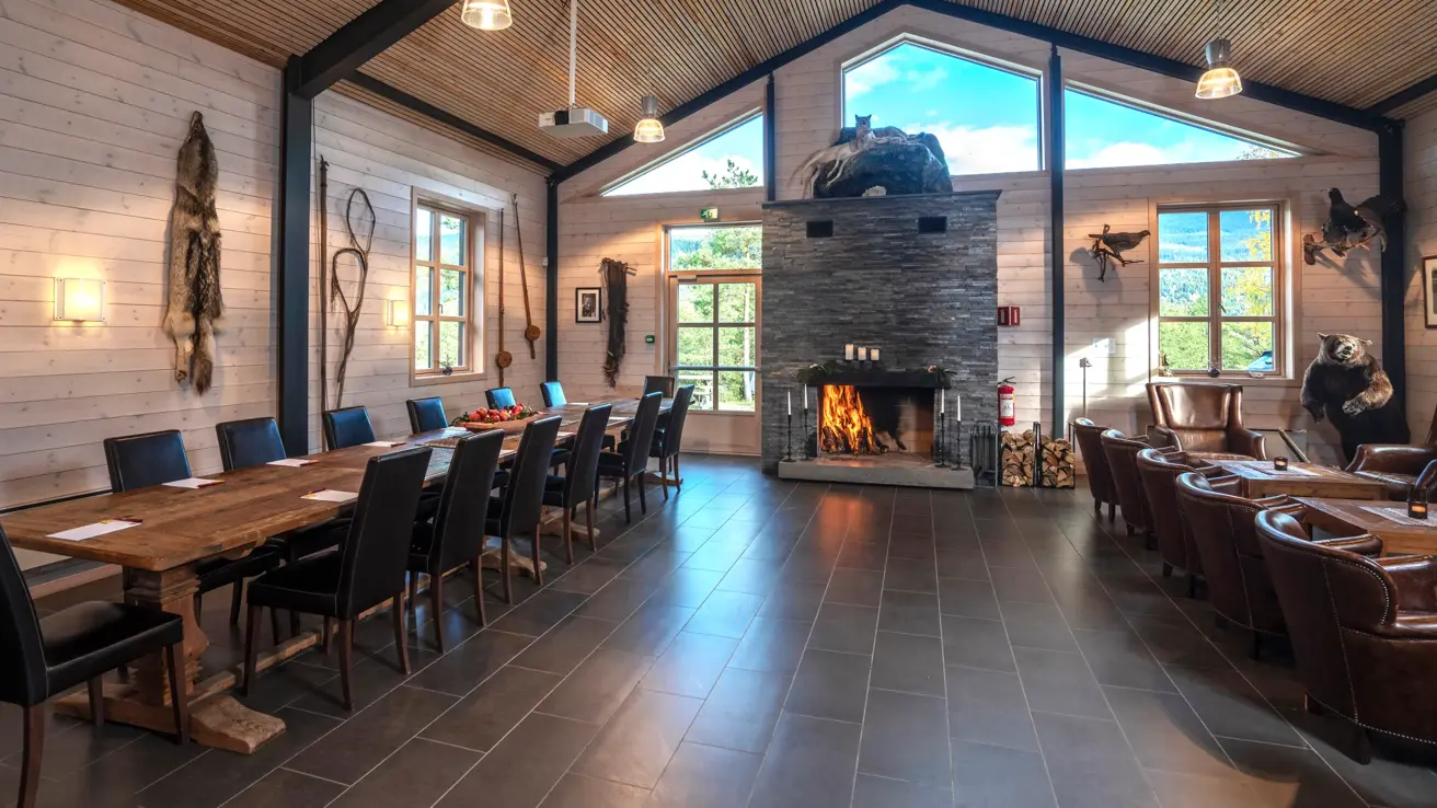 Peisstue dekket opp med langbord på venstre side og sittegrupper på høyre side.