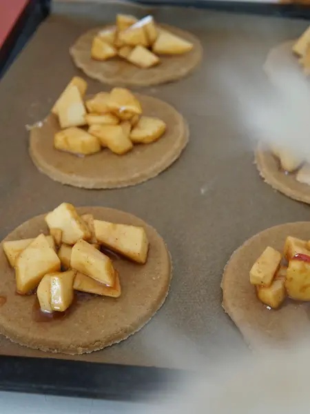 bakebrett med rundinger med deig med epleblanding på