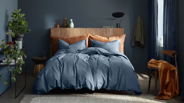 soverom med mørkeblå vegger, mørkeblått sengesett og med beigefargede pynteputer