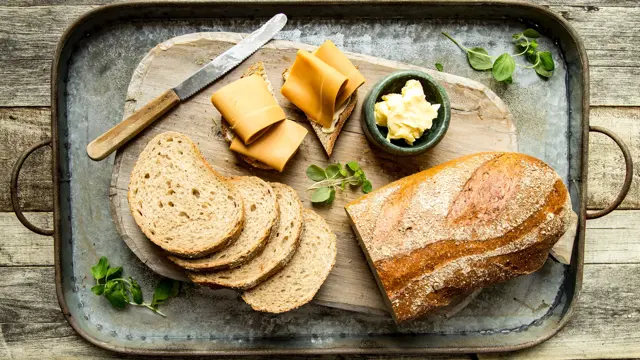 Baker Brun brød og oppskåret brødskive med brunost