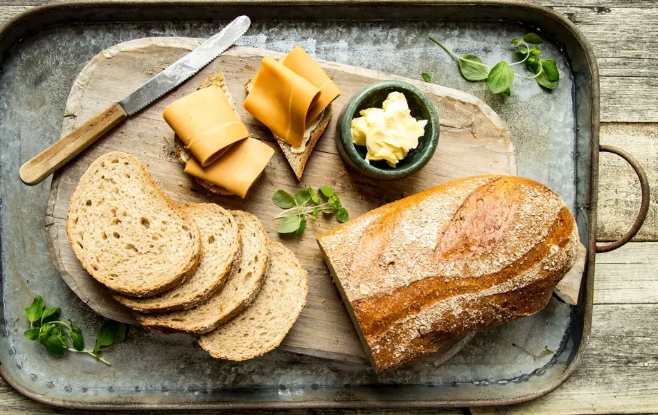 Baker Brun brød og oppskåret brødskive med brunost