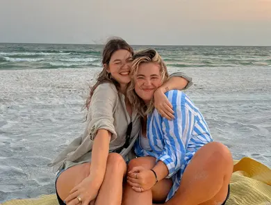 To damer som klemmer hverandre og sitter på en strand