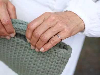 To hender med en diamantring holder en heklet grønn veske.