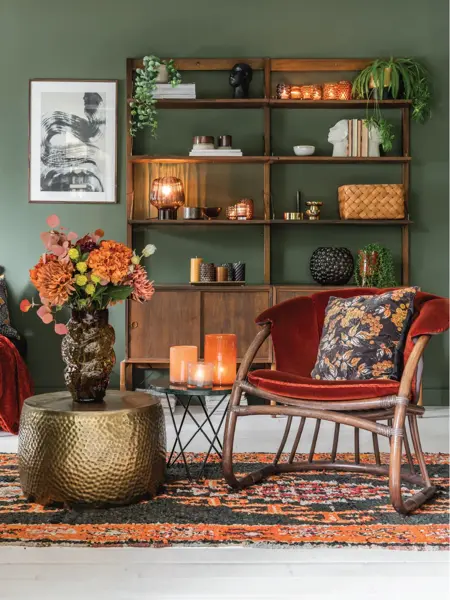 Grønn stue med rød stol og bokhylle dekket med dekor