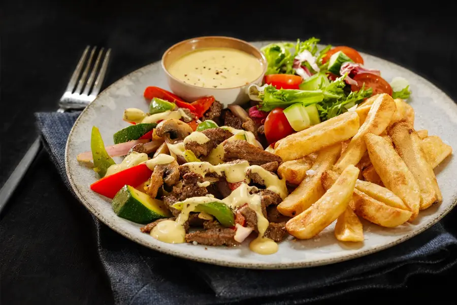 tallerken med biffstrimler, dressing, salat og pommes frites