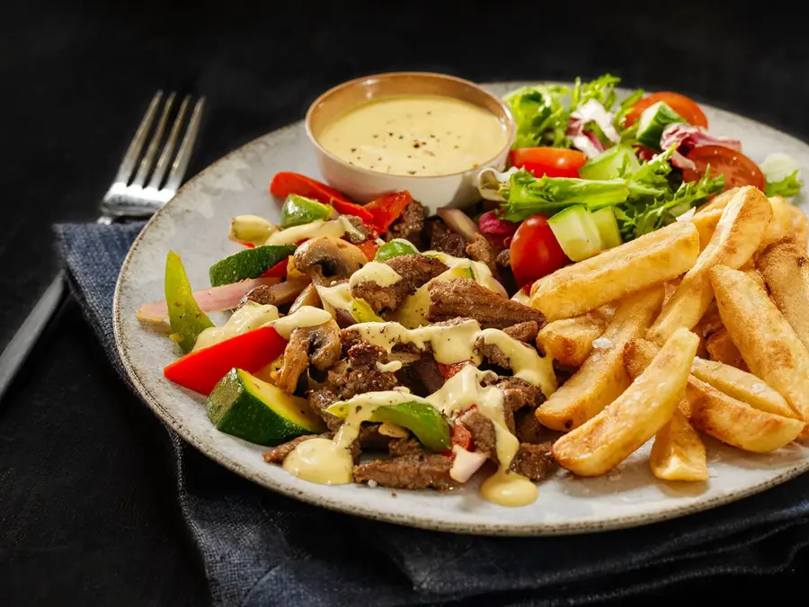 tallerken med biffstrimler, dressing, salat og pommes frites