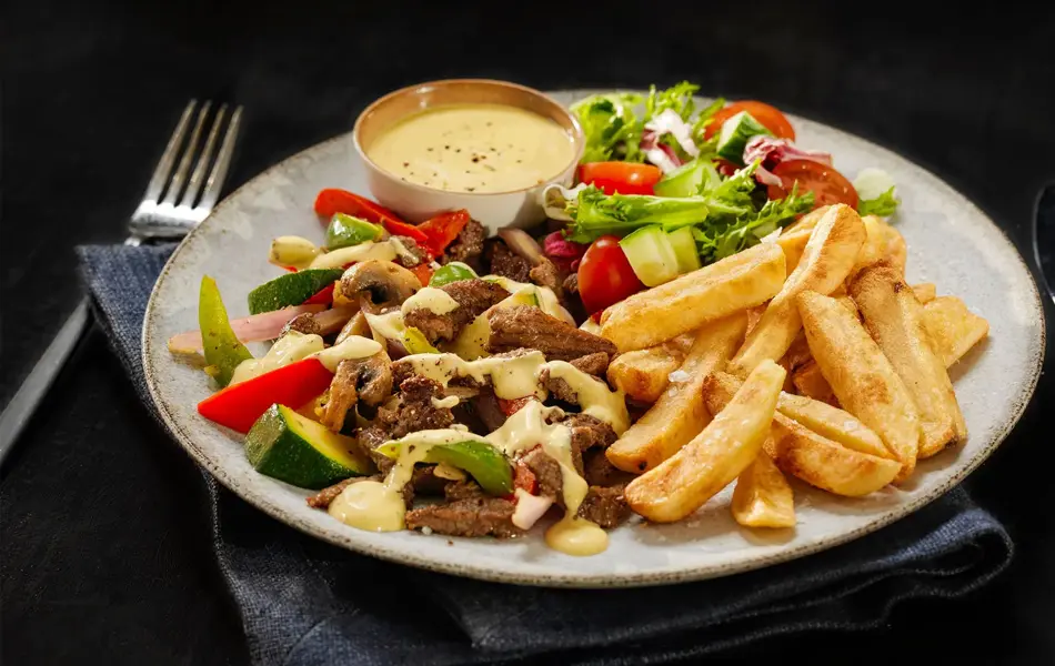 tallerken med biffstrimler, dressing, salat og pommes frites