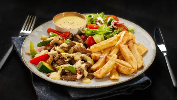 tallerken med biffstrimler, dressing, salat og pommes frites
