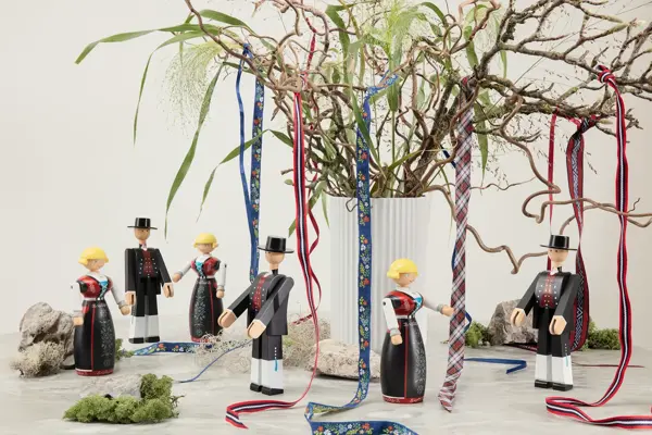 Bord med Kaj Boyesen bunadfigurer og en vase med grener.