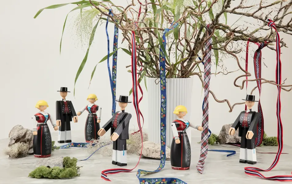 Bord med Kaj Boyesen bunadfigurer og en vase med grener.