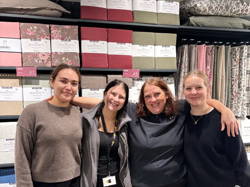tre mørkhårete og ei lyshåret jente står foran mange fargerike gardinpakker