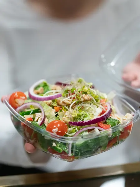 En dam som holder frem en bolle med salat fra spisestedet BIT