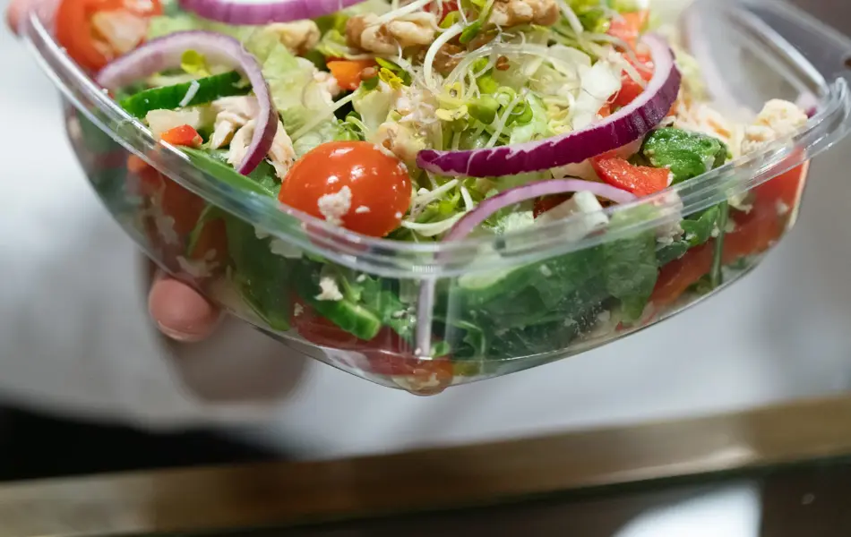 En dam som holder frem en bolle med salat fra spisestedet BIT