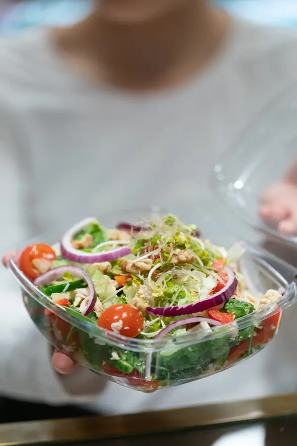 En dam som holder frem en bolle med salat fra spisestedet BIT