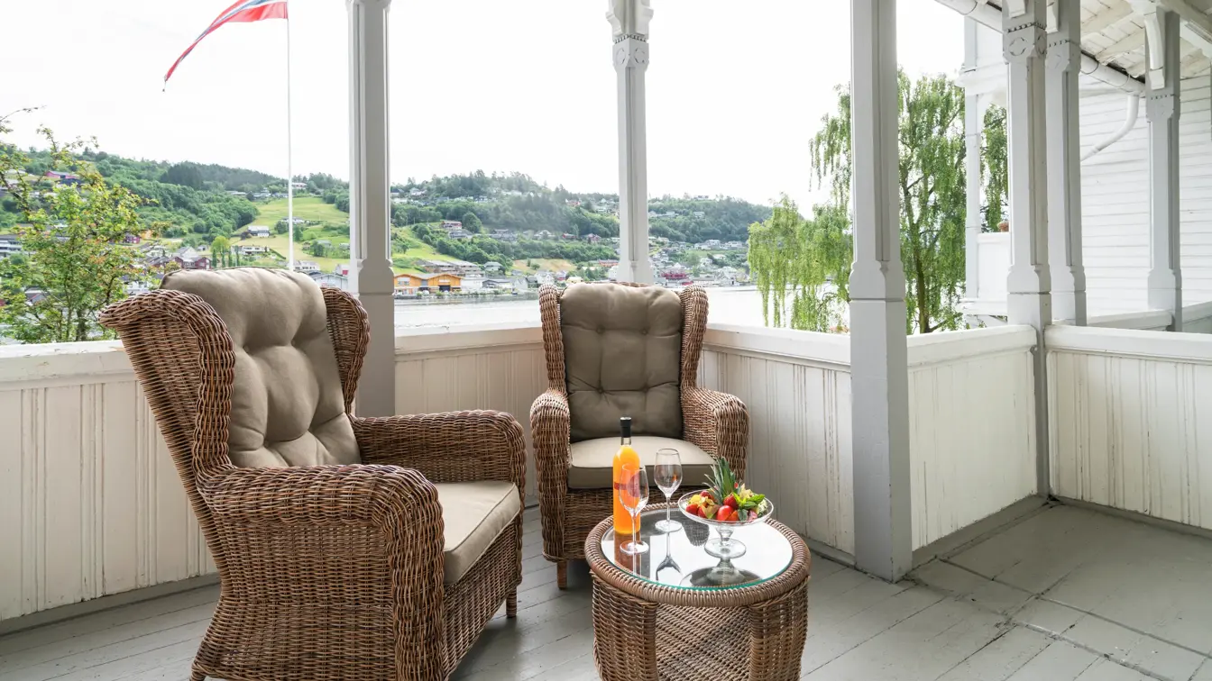 Veranda med peoner på bordet, eplemost i flaske og verandastoler på Thon Hotel Sandven i Nordheimsund