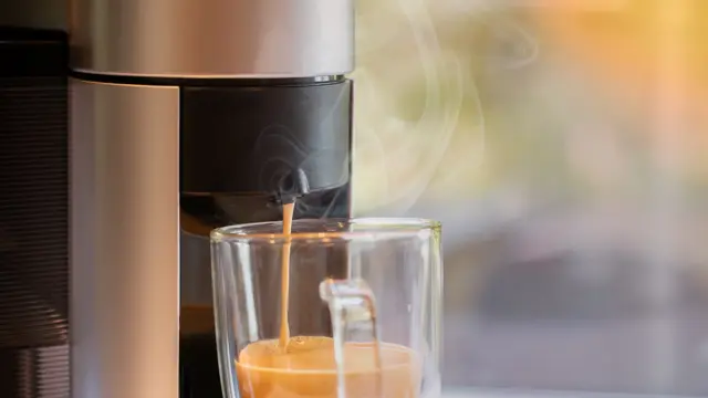 Espressomaskin fyller opp kaffekopp i glass