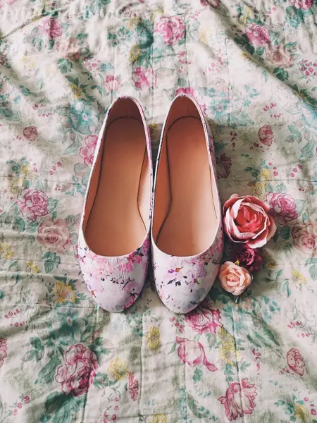 Ballerinsko med blomstermønster oppå et blomstrende stoff med tre roser ved siden av