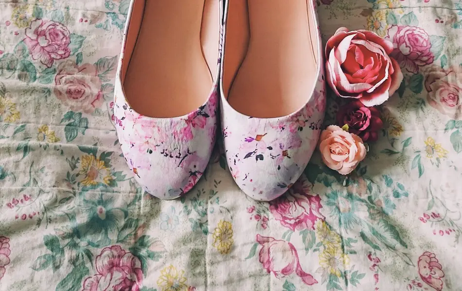 Ballerinsko med blomstermønster oppå et blomstrende stoff med tre roser ved siden av