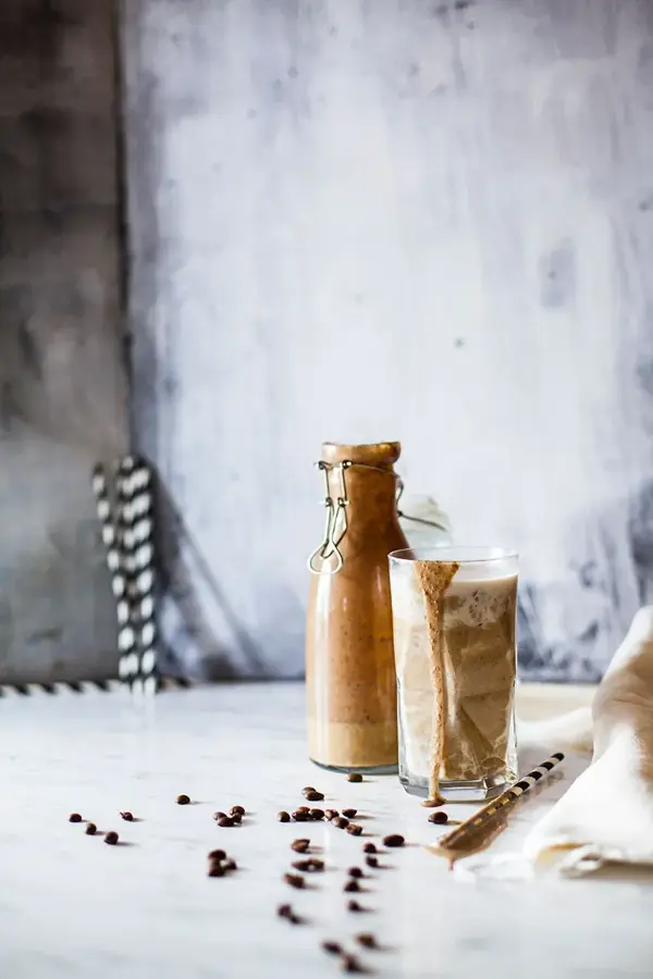 Kaffemilkshake i en glass og på et flaske med hvite og sorte papirsugerør
