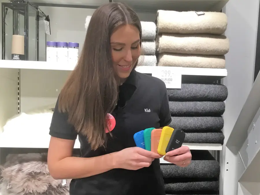 Dame med langt mørkt hår og sort t-skjorte som holder fem forskjellige sprayflasker i hånden