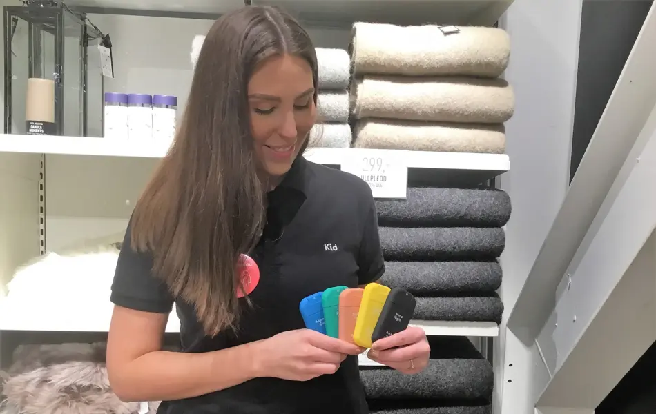 Dame med langt mørkt hår og sort t-skjorte som holder fem forskjellige sprayflasker i hånden