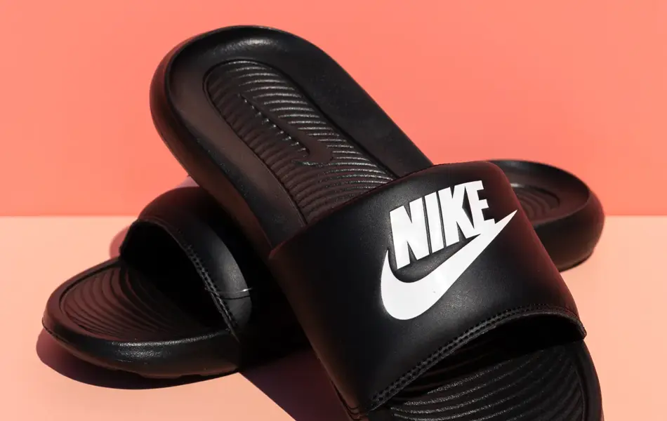 Sorte Nike slippers på ferskenfarget bakgrunn