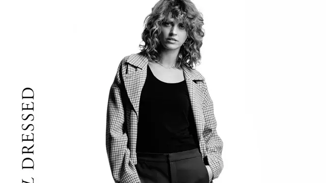 Damemodell krøllete blondt hår og ytterkåpe med småruter, ytterjakke boblejakke med hette, herremodell med trendy boblevest og damemodell med sort singlett og cropped dressbukse