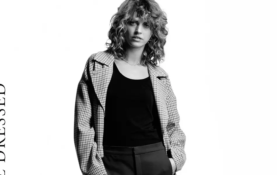 Damemodell krøllete blondt hår og ytterkåpe med småruter, ytterjakke boblejakke med hette, herremodell med trendy boblevest og damemodell med sort singlett og cropped dressbukse