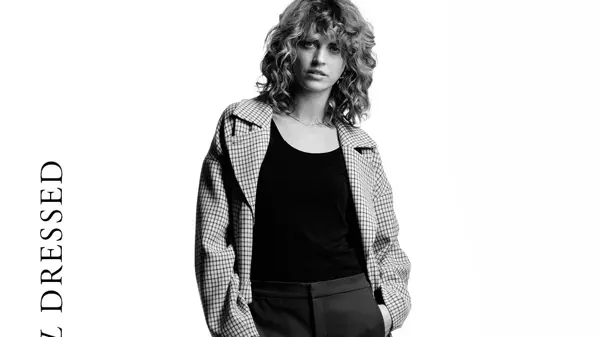 Damemodell krøllete blondt hår og ytterkåpe med småruter, ytterjakke boblejakke med hette, herremodell med trendy boblevest og damemodell med sort singlett og cropped dressbukse