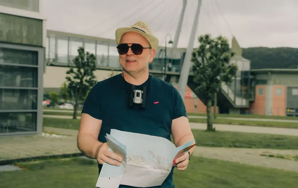 mann utenfor moa med hatt, solbrriller og kart