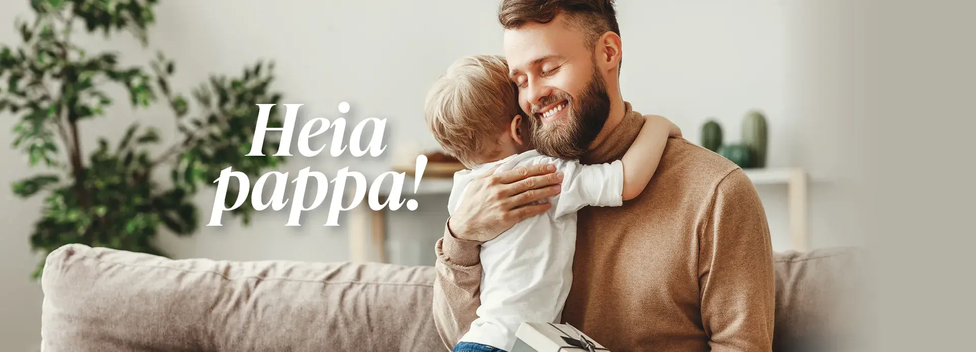 Liten gutt klemmer sin pappa som sitter i sofaen